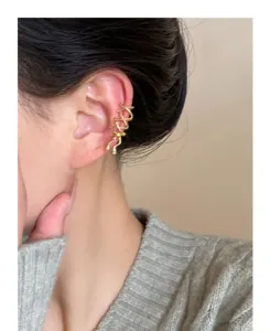 Detalle de brazalete de oreja cinta oro, clip de cartílago elegante sin perforación mujer.