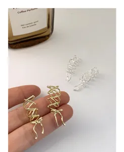 Primer plano detallado de pendientes de clip con lazo, elegante acabado metálico.