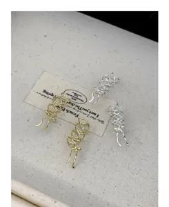 Detalle de elegantes pendientes de clip con lazo en metal dorado y plateado, diseño de nicho.