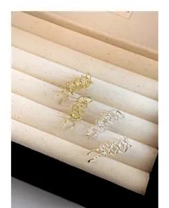 Detalle de cerca de mini pinzas para el cabello con lazo de metal dorado y plateado, joyero elegante.