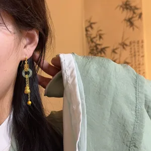 Exquisite Chinese style gold jade drop earring detail, featuring tassel and gourd design.