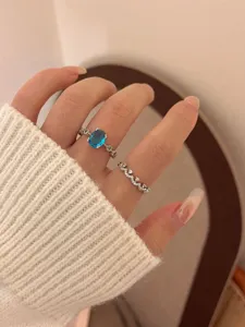 Elegant oval blue sapphire ring and rhinestone crown ring set, delicate minimalist jewelry detail.