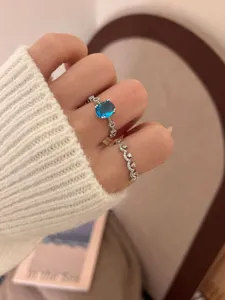 Delicate silver ring set with blue oval gemstone and sparkling diamond crown band detail.