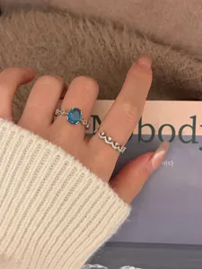 Elegant oval blue gemstone ring and sparkling crown band set for women, delicate fashion jewelry detail.