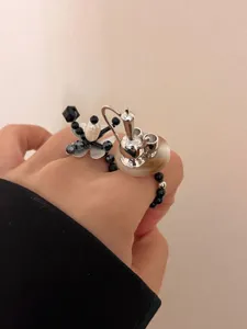 Detailed shot of Y2K beaded flower and silver teapot charm ring set, sweet cool elastic jewelry.