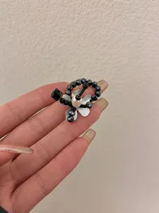 Beaded flower ring detail showcasing black crystals, silver petals, and a pearl center.