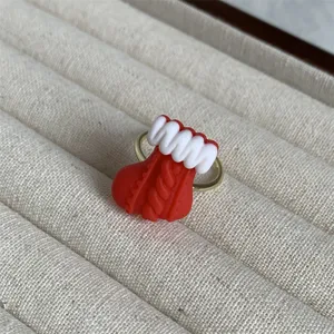 Nahaufnahme eines süßen Weihnachtsstrumpf-Harzrings auf einem beigen Schmuckpräsentationsteller.