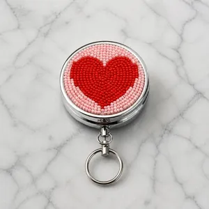 Vue de détail en gros plan du porte-clés cœur en perles métalliques et de la boîte de rangement.