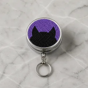 Gros plan détaillé du porte-clés boîte à pilules en métal perlé motif chapeau de sorcière chat.