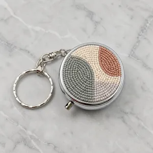 Vue détaillée de la boîte à pilules en métal avec perles de rocaille au design géométrique.