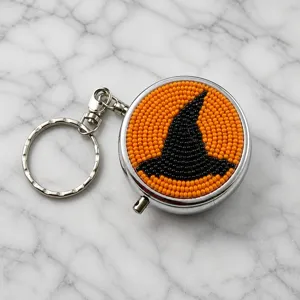 Gros plan détaillé du porte-clés chapeau de sorcière en perles orange et noires fait à la main.