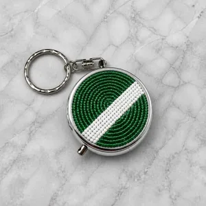 Gros plan du porte-clés boîte à pilules en métal perlé vert et blanc et ses détails précis.