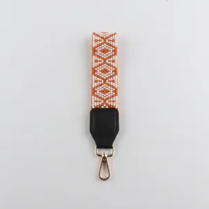 Handgemachte Perlen Handschlaufe mit geometrischem Muster, Lederlasche und goldenem Karabiner.
