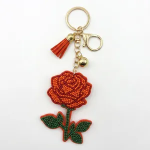 Porte-clés fleur de rose en perles avec quincaillerie dorée et pompon élégant pour sac.