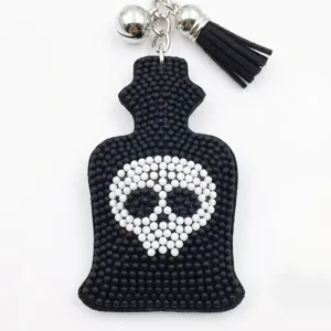 Gros plan sur le porte-clés tête de mort en perles vintage avec clochettes et pompon noir.