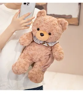 Cute plush teddy bear toy with plaid bib detail, soft curly brown fur holding display.