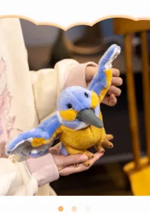 Close-up detail shot of the cute blue kingfisher plush toy with spread wings held in hand.
