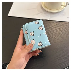 Close-up detail of a light blue trifold mini wallet with cute cow prints and coin card slots.