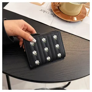 Detailed view of women short black wallet with cute white daisy embroidery, zipper and card slots.