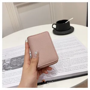 Detalle de un elegante tarjetero texturizado de color rosa con cierre de cremallera.