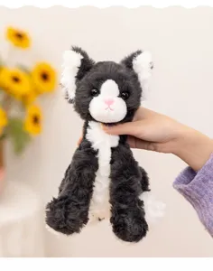 Detailed view of a cute black and white plush cat toy, soft fluffy doll for kids companionship.