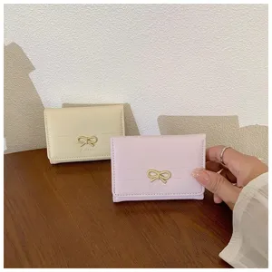 Detailed view of the cute Korean style short wallet with metal bowknot decoration in pink and cream.