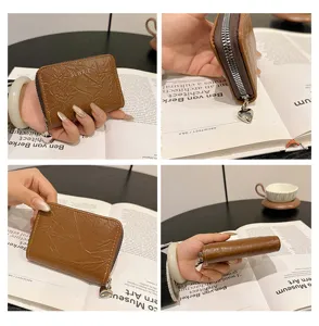 Close-up detail of the brown PU leather card holder showing zipper and cute heart charm.