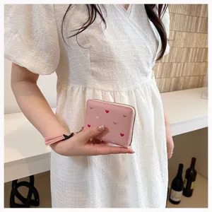 Pink PU leather short wallet detail showing cute embroidered hearts and tassel charm.