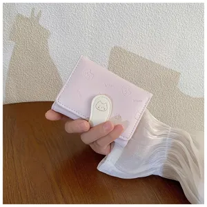 Vista ravvicinata del piccolo portafoglio rosa con stampa di gatto in rilievo e chiusura a pressione.