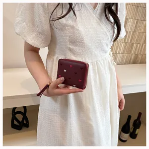 Detailed shot of women short pu leather wallet with cute embroidered hearts and tassel zipper.