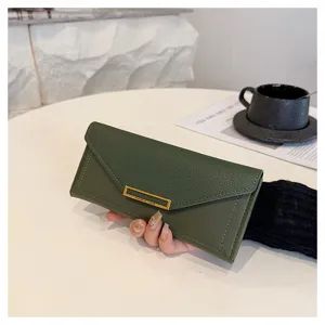 Detailed shot of dark green women's long envelope wallet with gold clasp and card slots.