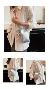 Detailed view of the metallic silver mini phone bag with cute elephant charm and shoulder strap.