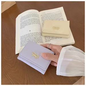 Cute mini trifold wallet for women with elegant bow metal decor and multiple card slots.
