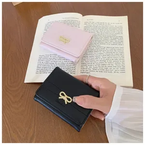 Close-up detail of a minimalist women short wallet with bow decor on a book background.