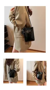 Cute mini black crossbody phone bag for women with elephant pendant, detailed wearing view.