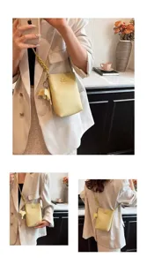 Detailed view of the stylish yellow phone bag featuring a cute elephant charm and braided strap.