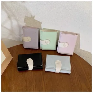 Primo piano di mini portafogli pastello con bottoni a pressione e decori di gatti.