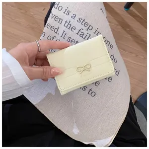 Detail shot of a small pale yellow trifold wallet with a cute metal bow for women.