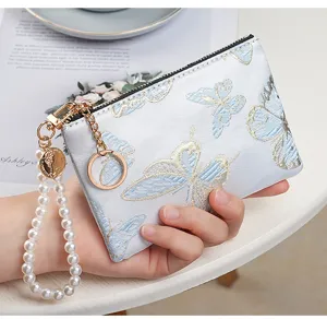Detailed view of the women's embroidered butterfly coin purse with pearl wrist strap.
