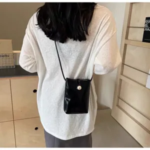Black patent leather crossbody phone bag for women with pearl button, stylish summer bag.