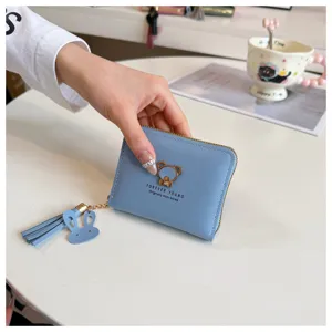 Close-up detail of stylish blue short wallet featuring cute bear logo and lovely rabbit charm.