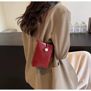 Chic small crossbody phone bag detail, dark red leather with pearl clasp for women.