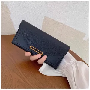 Detailed view of the elegant black long wallet with chic gold metal decor. Perfect close-up.