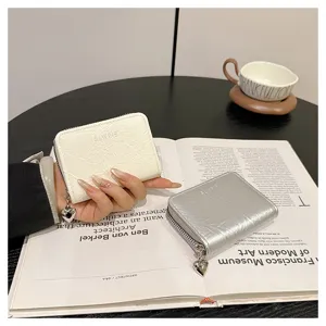 Close-up of stylish mini card wallet with heart pendant and textured faux leather surface.