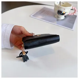 Black short wallet detail view featuring gold zipper and chic tassel pendant, elegant compact design.
