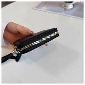 Black short zipper wallet for women with tassel pendant, compact coin purse side detail view.