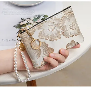 Detailed view of Chinese style embroidered coin purse with pearl wrist strap and golden zipper.
