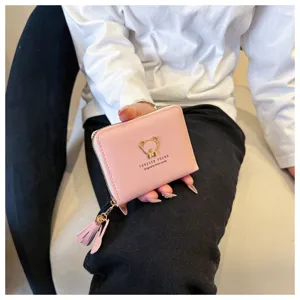 Pink short women's wallet with cute bear metal emblem, zipper closure, and tassel charm.