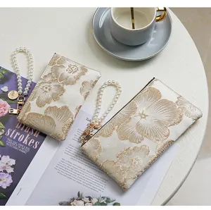 Detailed view of Chinese style embroidered long wallet with pearl wristlet strap and zipper.