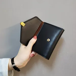 Close-up detail of women short leather wallet, displaying interior card slots and metal snap.